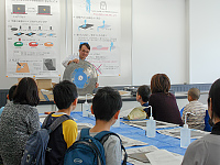 化石を含む岩石を切断する説明をしています。